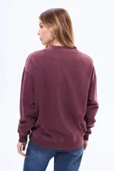 Buzo de cuello redondo en color bordó con efecto lavado, manga larga y detalle de tachas metálicas en la parte superior del pecho.