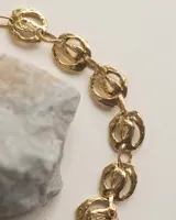 Pulsera de eslabones circulares con diseño orgánico y textura irregular, elaborada artesanalmente en metal con acabado dorado.
