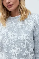 Sweater de punto color rojo con cuello redondo, mangas largas y bordado floral en tono rosado en la parte frontal.