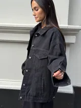 Campera clásica de jean negra con cuello camisero, bolsillos frontales y detalles de brillos plateados.