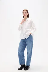 Camisa de algodón blanca, de corte clásico con cuello camisero, cierre frontal con botones, mangas largas con puños y bolsillo frontal en el pecho.