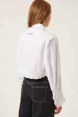 Camisa blanca de popelina con volados en cuello, puños y pechera.