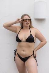 Conjunto de bikini negro con corpiño triangular con tirantes finos y bombacha con tiras ajustables en los laterales.