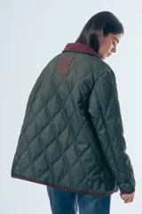 Campera acolchada de diseño matelasse con pespuntes ondulados, cuello clásico en contraste y cierre frontal con botones. Presenta bolsillos frontales con ribetes a tono y calce relajado.