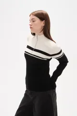 Polera de punto acanalado con diseño bicolor en blanco y negro, cuello alto con cierre frontal y manga larga.