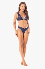 Conjunto de bikini azul marino con volados bordados a mano con hilo blanco. El top tiene copas extraíbles, tirantes ajustables y lazo en la espalda. La bombacha es tradicional con bordado a mano. El tejido se adhiere muy bien a la piel, proporcionando mayor comodidad y una compresión suave, además de un ligero brillo.