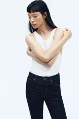 Jean de tiro alto con corte acampanado desde la rodilla, confeccionado en denim oscuro con cinco bolsillos y cierre frontal con botón.