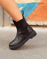 Bota tipo Chelsea de cuero negro con caña media, paneles laterales elásticos y suela track dentada.