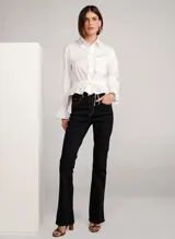 Pantalón de jean bootcut color negro con costuras en color naranja, tiro alto, pretina con trabillas, cierre frontal con cremallera y botón, y cinco bolsillos.