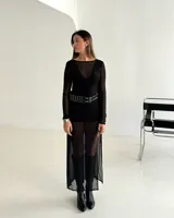 Vestido largo de microtul transparente, con mangas largas y cuello redondo. Presenta un diseño de doble capa con una pieza interior opaca tipo mini vestido y una capa exterior traslúcida que llega hasta los tobillos.