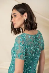 Vestido largo de tul verde con bordado floral al tono, corte sirena y mangas cortas.