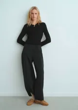 Jersey de canalé color negro, con cuello camisero, manga larga y diseño entallado. Cuenta con detalle de botón efecto joya.