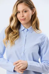 Camisa celeste rayada de corte holgado, con cuello camisero clásico y mangas largas.