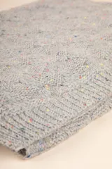 Bufanda rectangular tejida color gris con pequeños puntos de color.