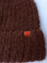 Gorro de lana marrón con etiqueta de cuero con logo en el borde.