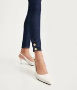 Pantalón skinny jeans azul oscuro con trabillas en la cintura, bolsillos y detalle de pespuntes contrastantes. La pieza también tiene dos botones dorados a cada lado de la barra.