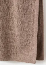Falda larga de punto fino, de corte recto y color marrón, con cintura elástica decorada con pequeños apliques metálicos.