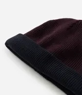 Gorro de punto con doblez, diseño reversible bicolor en tonos azul marino y bordó, confeccionado en lana acrílica.