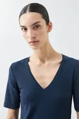 Remera de punto con acabado brillante, cuello en V y mangas cortas.