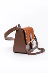 Bolso tipo cartera de mano color marrón, confeccionado en cuerina y gamuza, con solapa frontal decorada con tachas metálicas plateadas y una tira con hebilla central. Cuenta con un asa corta para llevar al hombro.