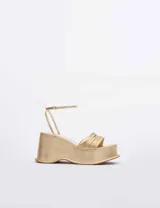 Sandalias de plataforma con taco cuña, color dorado metalizado. Presentan un diseño de tiras finas múltiples en el empeine y una tira ajustable con hebilla en el tobillo.