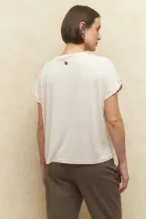 Remera color beige de manga corta con cuello redondo y detalle de pliegues en los hombros.