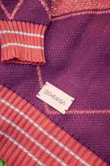 Saco tejido de punto con diseño de rombos en color bordó y naranja, con detalles en lurex. Presenta cuello redondo, cierre frontal con botones y mangas abullonadas con puños acanalados.