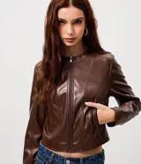 Campera de cuero sintético color marrón, con cuello redondo, cierre frontal y bolsillos laterales con cremallera. Presenta costuras verticales decorativas que le dan un diseño estructurado.