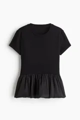 Top de punto suave negro con cuello redondo, manga corta y bajo con volados de tela satinada.