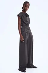 Pantalón de tiro alto, color gris oscuro, de corte amplio y pierna ancha. Presenta cintura elástica y pliegues frontales.