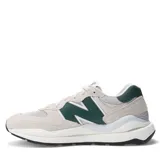 Championes urbanos New Balance modelo 57/40, con diseño en capas de gamuza beige y malla, destacando el logo N en color verde oscuro. Presentan una entresuela voluminosa y suela de goma negra.