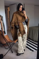 Chal de tejido liviano en color bronce con acabado brillante y flecos largos en todo el contorno. Presenta una textura tejida y una caída fluida.