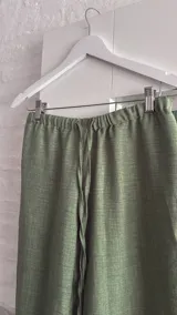 Pantalón ancho de tiro bajo, color verde claro, con cordón ajustable en la cintura y tiras laterales ajustables.