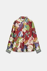 Camisa de cuello solapa y manga larga con puños a rayas. Confeccionada en tejido satinado con estampado floral multicolor sobre base roja. Cierre frontal con botones forrados.