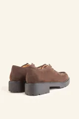 Zapato tipo wallabee de gamuza azul con costuras blancas a la vista y suela de goma negra con plataforma.