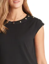 Blusa negra de punto elástico con caída fluida, cuello redondo y apliques de tachas doradas circulares en el cuello y los hombros. Tiene manga casquillo y ruedo redondeado.