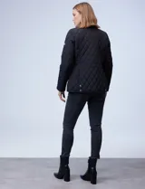 Campera capitoneada azul marino con cuello y ribetes en cuero marrón, marca Michael Kors. Abertura central con botones metálicos dorados, bolsillos verticales delanteros y logo metálico en el brazo.