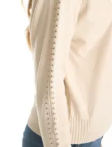 Buzo tejido color beige de manga japonesa, con detalle de tachas metálicas a lo largo de las mangas. Presenta puños y ruedo acanalados.
