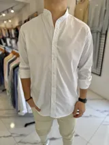 Camisa blanca de manga larga con cuello mao y cierre frontal de botones, diseñada con un corte clásico.