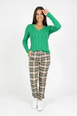 Pantalón de corte recto con estampado de cuadros escoceses en tonos beige, negro y verde. Presenta bolsillos delanteros funcionales y cierre frontal con botón.