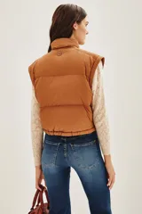 Campera puffer color tostado, con cierre frontal y botones a presión, cuello alto y puños tejidos acanalados.