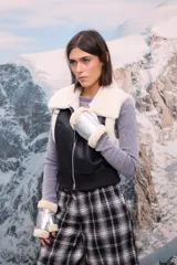 Chaleco de cuero sintético negro con interior y cuello de piel sintética blanca, cierre frontal y cintura elástica ajustada.