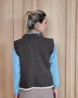 Chaleco tejido de punto con diseño abstracto en bloques de color marrón y turquesa, con cuello redondo y terminaciones acanaladas.