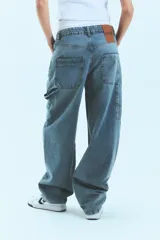Jean de corte baggy y tiro bajo, en color azul lavado. Presenta un diseño holgado con presillas anchas y cierre frontal con botón metálico.