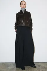 Pantalón de tiro medio con diseño de raya diplomática, corte wide leg y detalle de pinzas en el delantero. Cuenta con cintura con trabillas, bolsillos laterales y cierre frontal con cremallera, botón y ganchos metálicos.