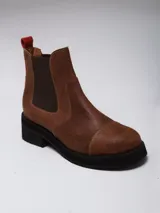 Botas tipo Chelsea de gamuza color marrón oscuro, con paneles elásticos laterales a tono, puntera redondeada y suela plana de goma negra.