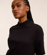 Remera negra de algodón, corte amplio, cuello alto en punto roma y mangas cortas.