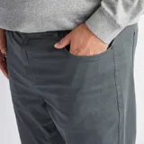 Pantalón de corte slim en color verde oscuro, con diseño de cinco bolsillos y cierre frontal con botón y cremallera.