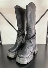 Botas negras de cuero vegano con caña alta, polainas arrugadas y suela track.