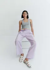 Pantalón wide leg de tiro medio con diseño de rayas verticales finas en color lila. Presenta bolsillos laterales, bolsillos traseros de ribete, trabillas para cinturón y cierre frontal oculto con botón, gancho y cremallera.